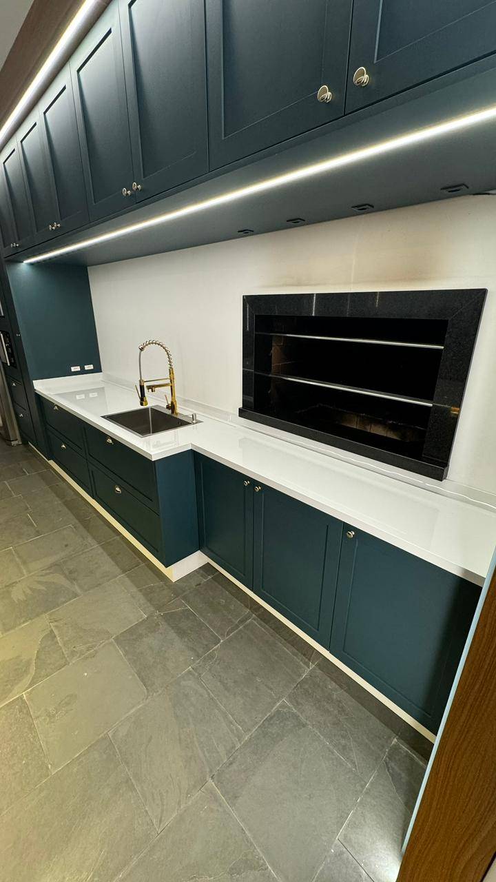 Espaço gourmet completo com ilha em pedra e revestimento em lâmina ultracompacta.